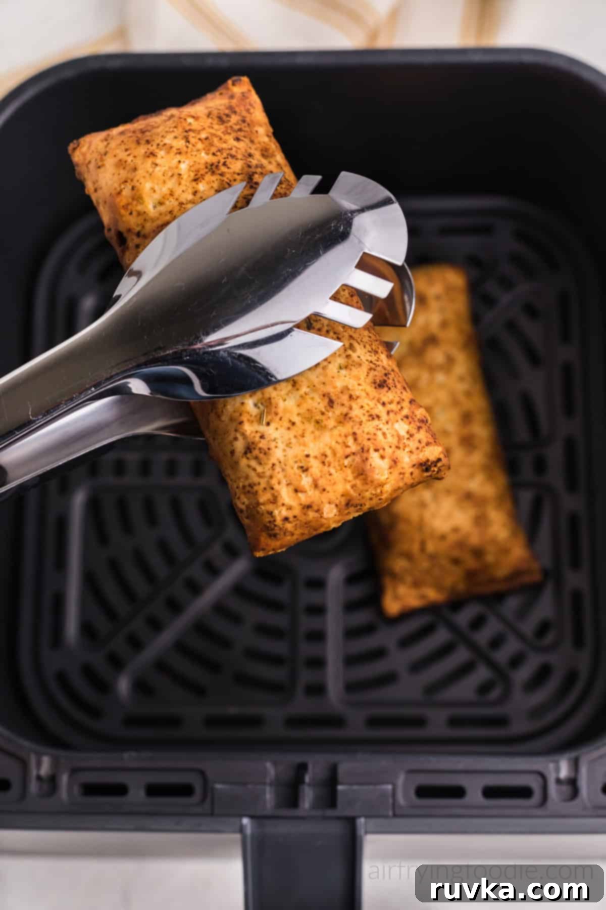 Crispy Air Fryer Hot Pockets 2 Hot pocket in air fryer basket and hot pocket in tongs over the air fryer basket. Ready to serve