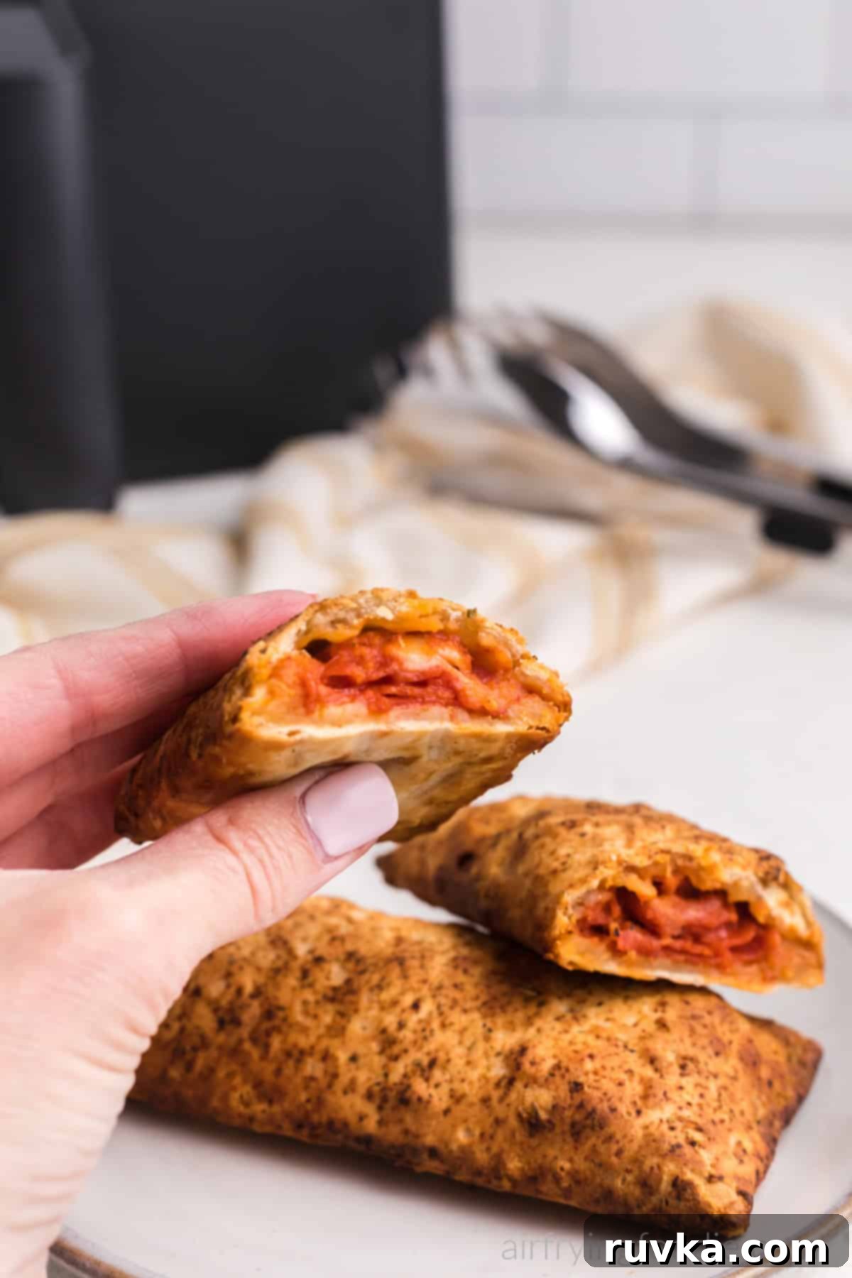 Crispy Air Fryer Hot Pockets 8 Hand holding a half of an air fried hot pocket, ready to eat.