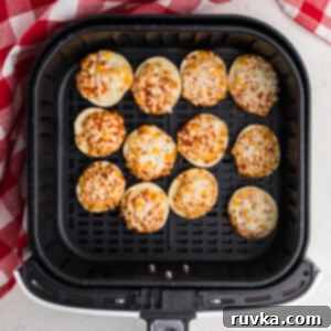 Air Fryer Bagel Poppers 7 Bagel bites in the basket of the air fryer - cooked and ready to eat.