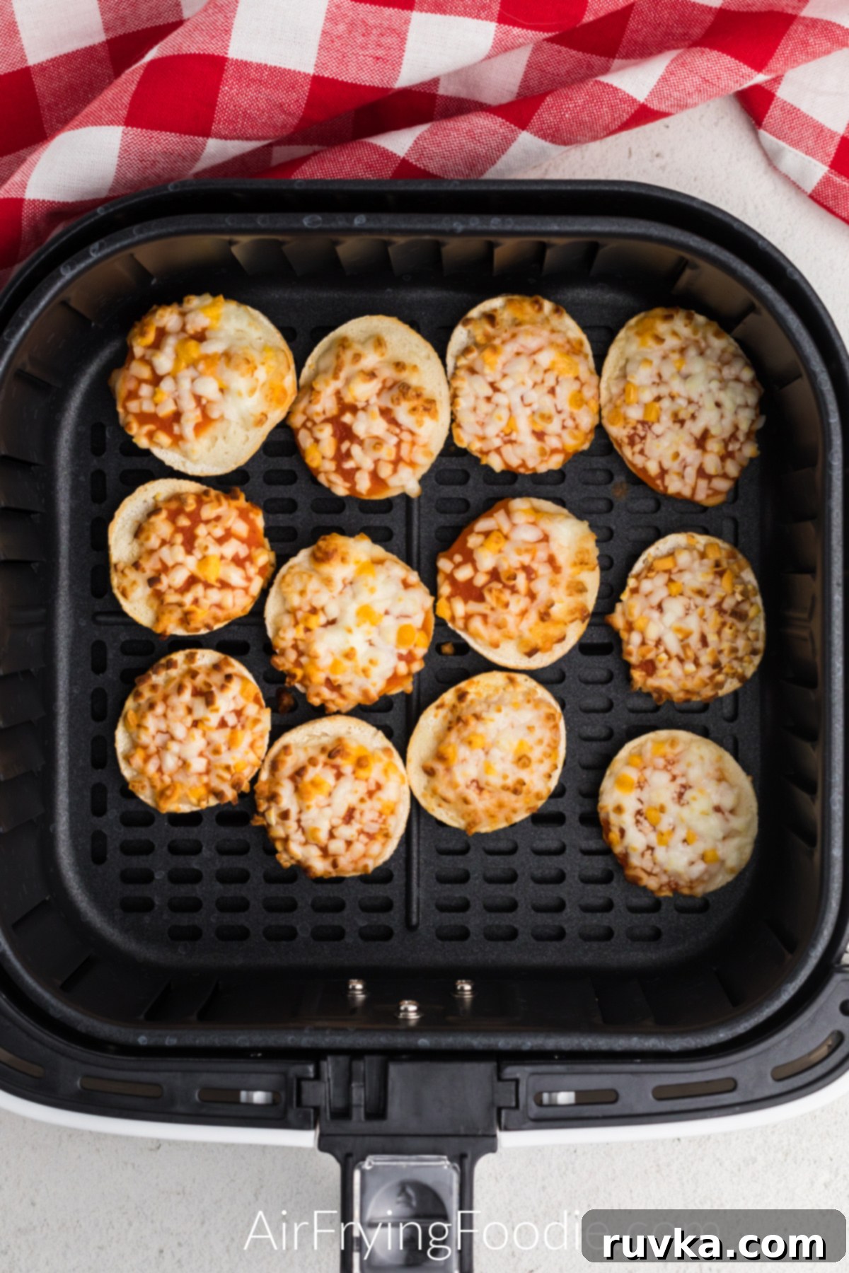 Air Fryer Bagel Poppers 4 Air Fried Bagel bites in the basket of the air fryer.