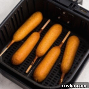 Golden Crispy Air Fryer Corn Dogs 7 Golden corn dogs in the air fryer basket after being cooked