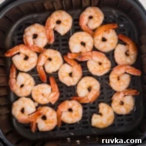 Easy Air Fryer Frozen Shrimp 8 Juicy orange shrimp in the air fryer basket after being cooked from frozen.