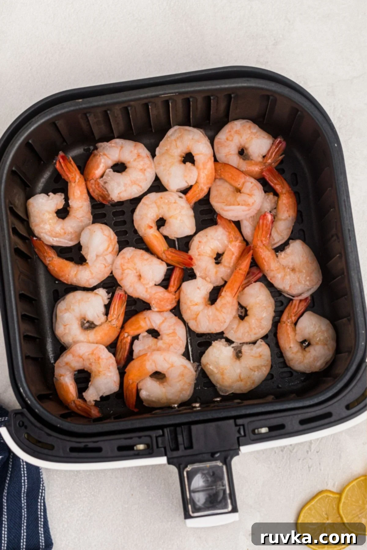 Easy Air Fryer Frozen Shrimp 4 Frozen pink shrimp in the air fryer basket arranged in a single layer before being cooked.