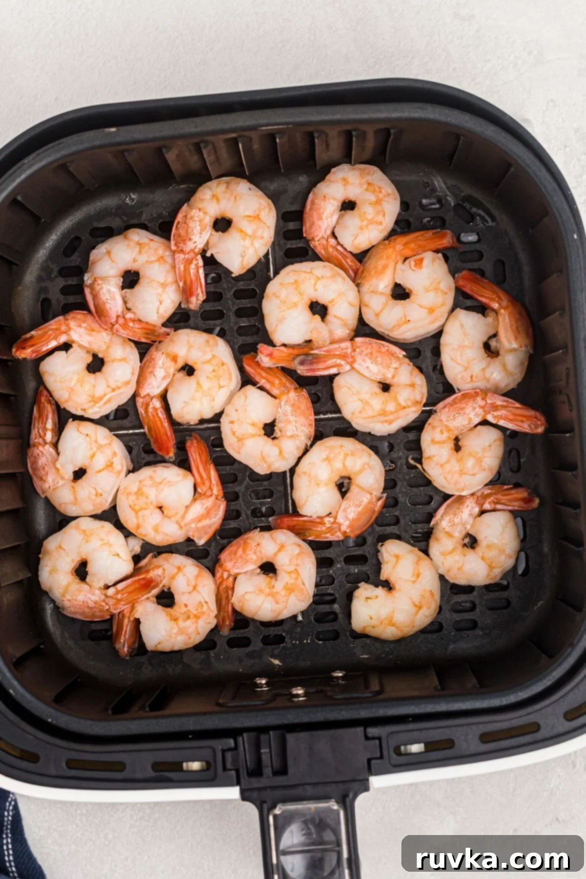 Easy Air Fryer Frozen Shrimp 5 Orange frozen shrimp in the air fryer basket before being cooked