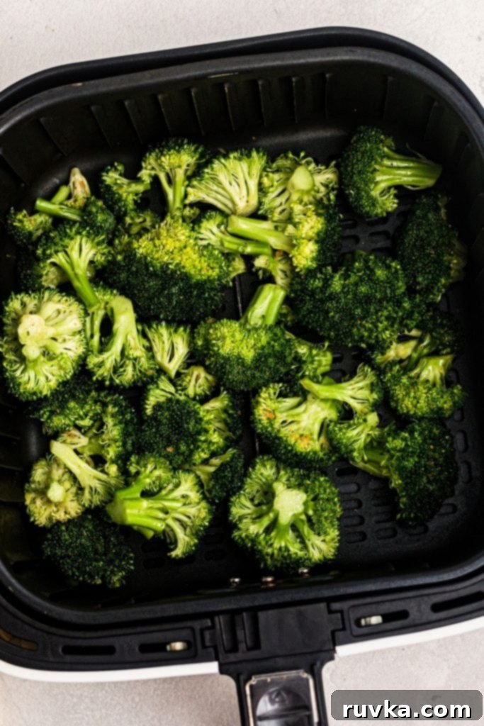 Crispy Air Fryer Broccoli 5 Uncooked seasoned broccoli in an air fryer basket.