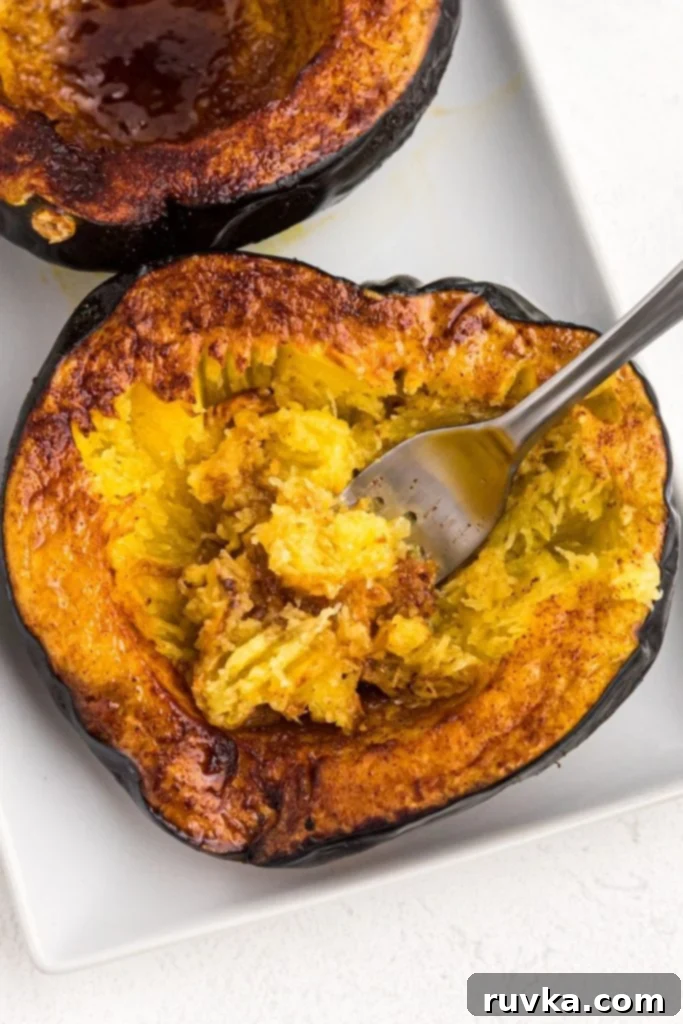 Crispy Air Fried Acorn Squash 2 Golden brown cooked acorn squash on a white plate with a fork scooping insides.