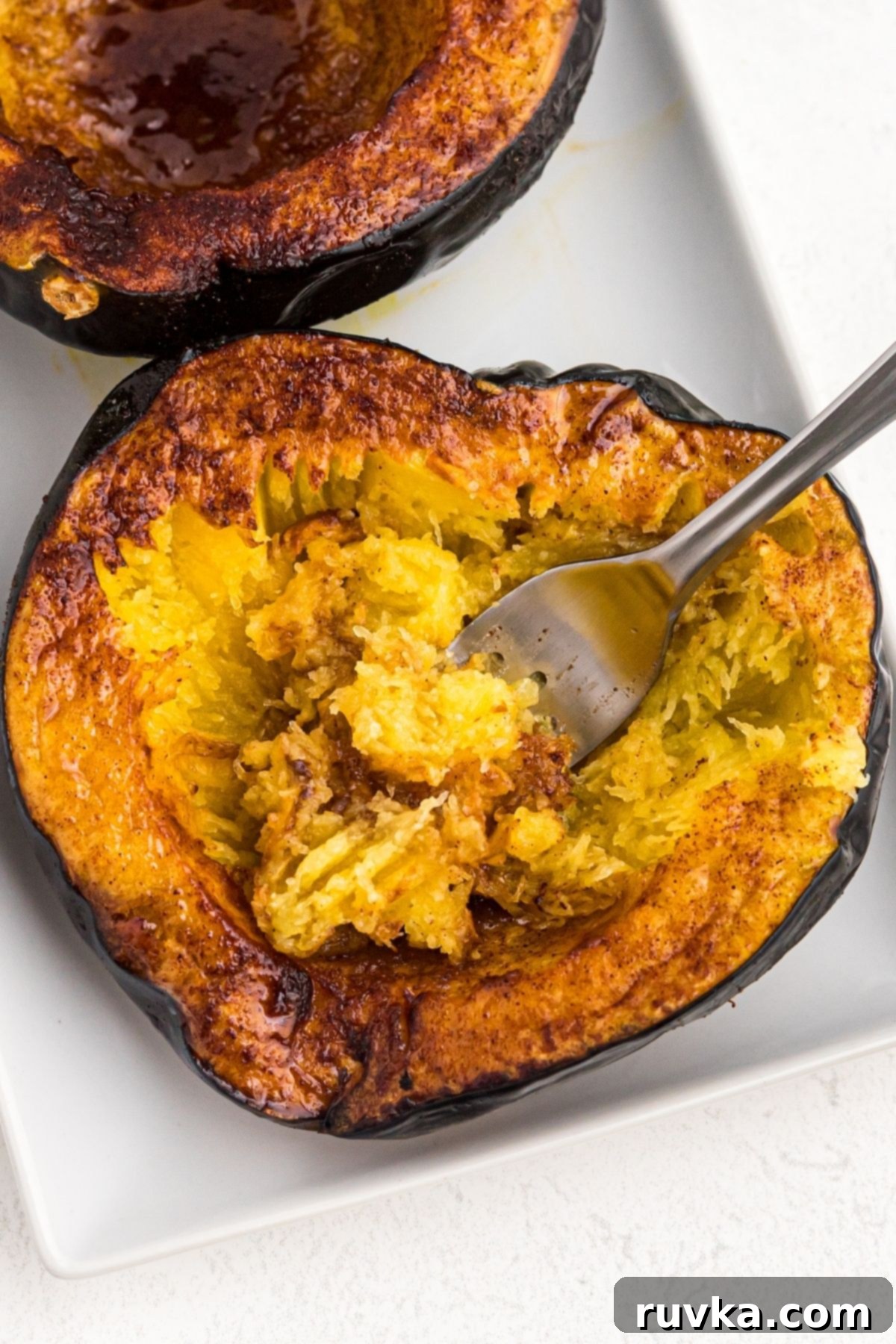 Crispy Air Fried Acorn Squash 8 Golden cooked acorn squash on a white plate with a fork bite in the center of the squash.
