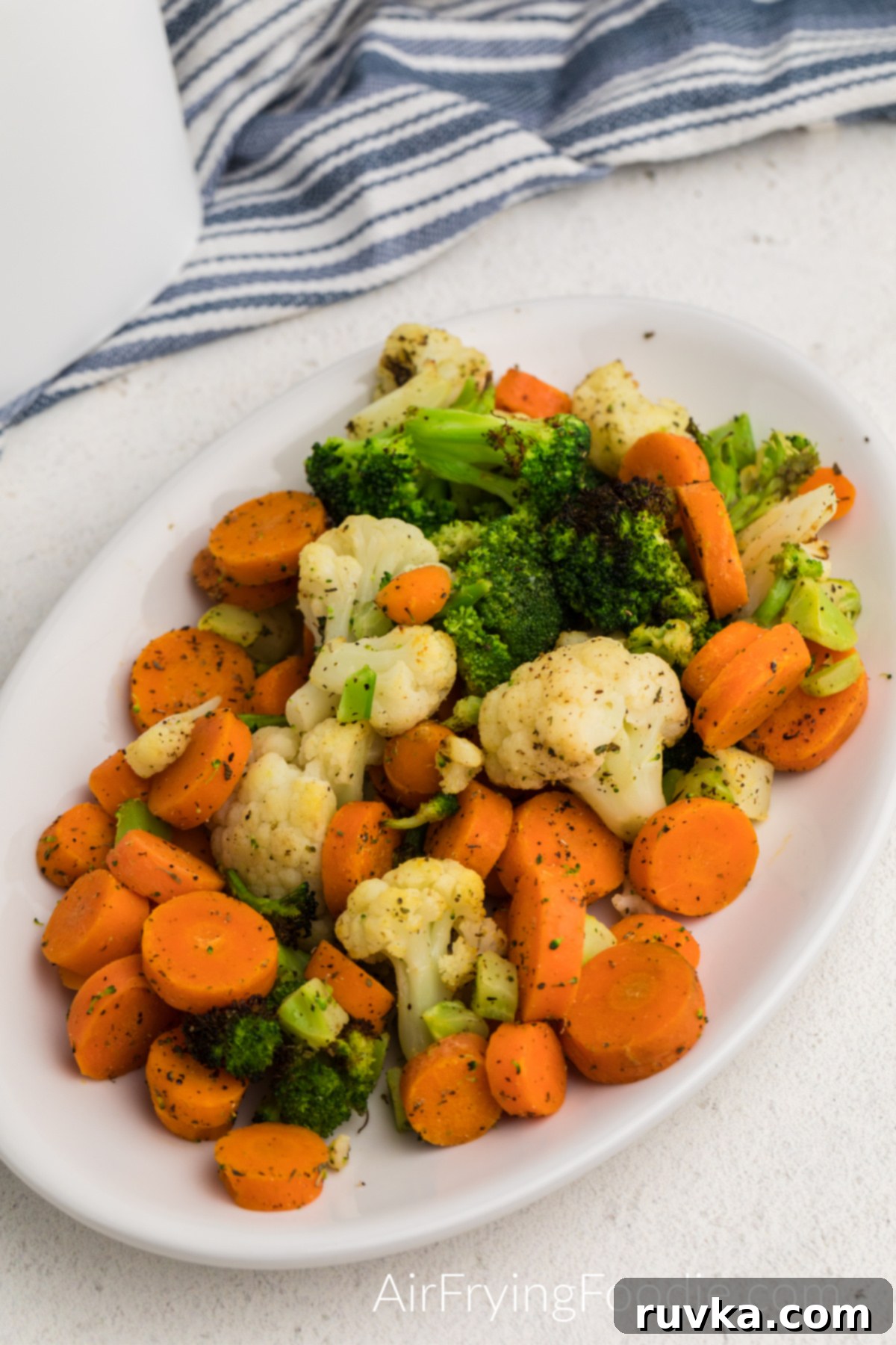 Crispy Air Fried Frozen Vegetables 2 A serving of crispy, seasoned air-fried frozen mixed vegetables on a white plate, ready to be enjoyed.