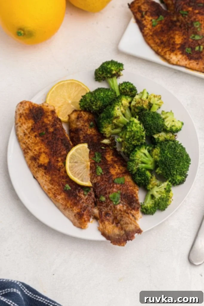 Crispy Air Fryer Tilapia 2 Golden seasoned tilapia cooked and served on a white plate with broccoli