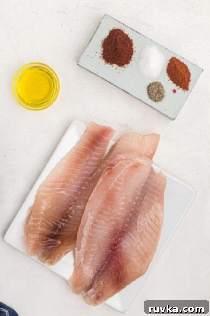 Crispy Air Fryer Tilapia 3 Uncooked tilapia filets on a white plate with olive oil and seasonings.