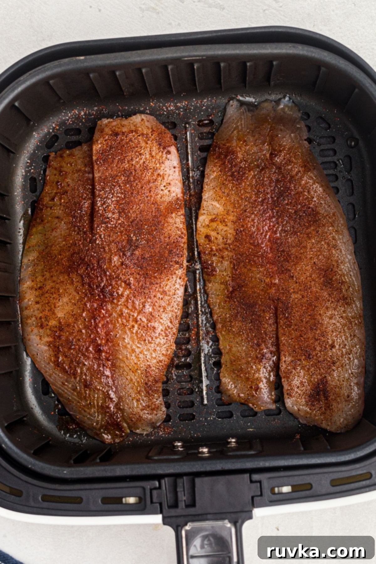 Crispy Air Fryer Tilapia 5 seasoned tilapia filets in the air fryer basket before being cooked