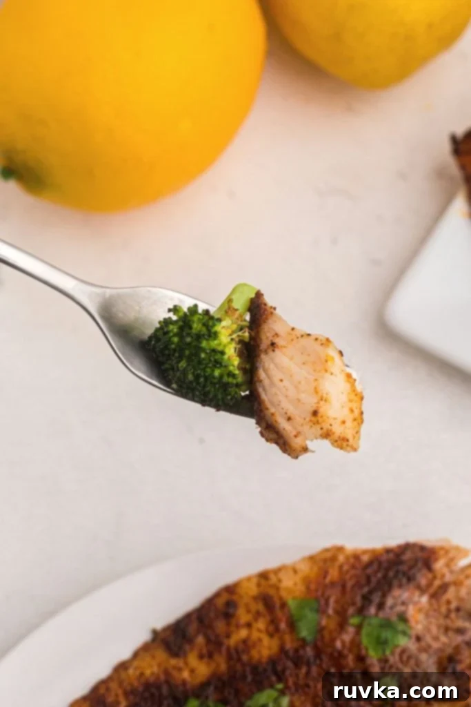 Crispy Air Fryer Tilapia 8 Fork bite of cooked tilapia served with broccoli