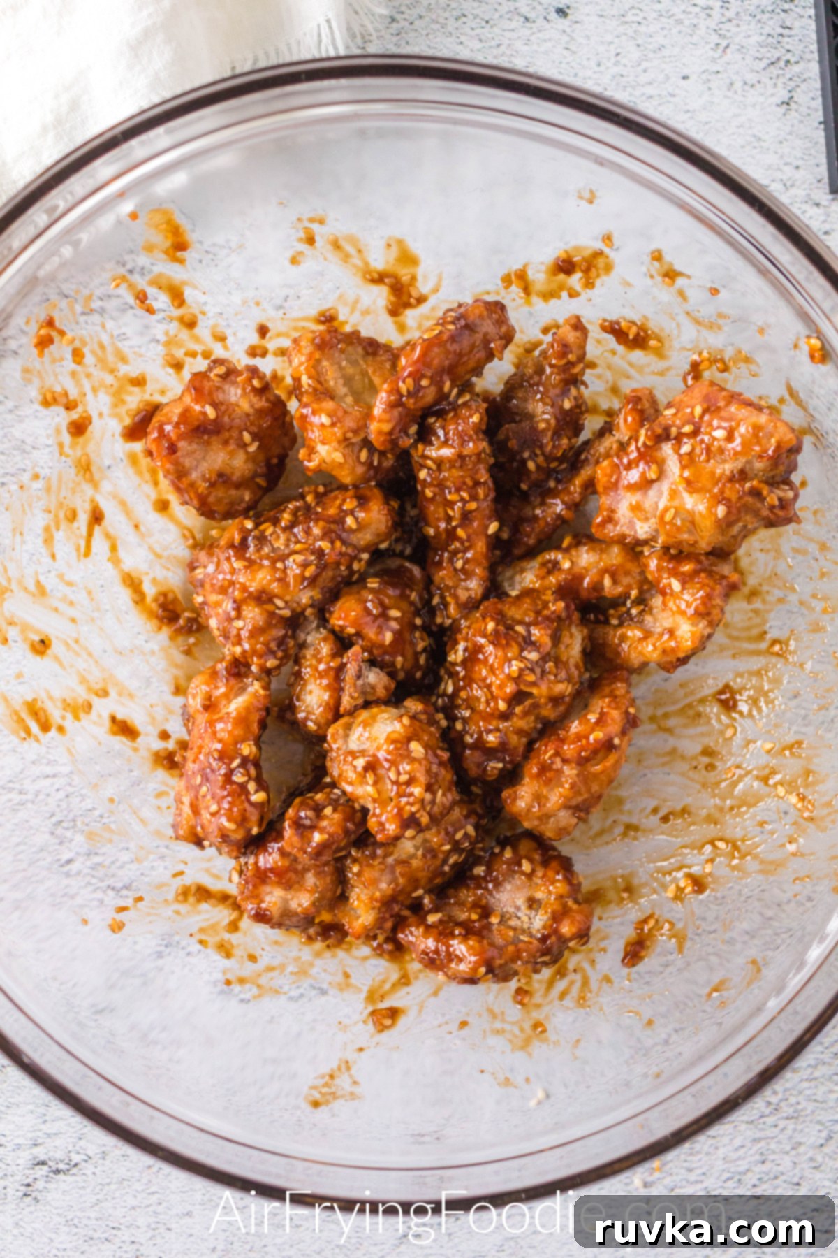 Crispy Golden Air Fryer Sesame Chicken 6 Chicken tossed in sauce and in a bowl before serving.