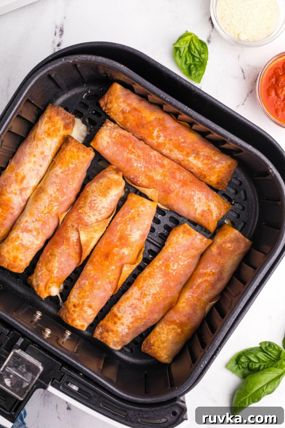 Super Bowl Air Fryer Snacks 12 Golden crispy pizza egg rolls, filled with cheesy goodness, beautifully arranged in the air fryer basket.