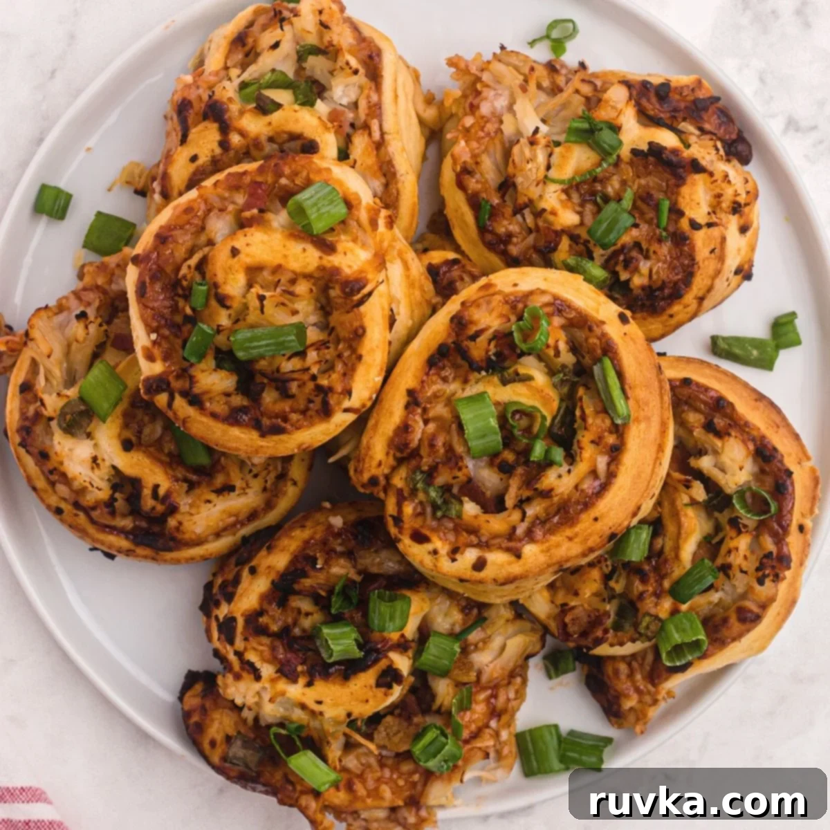 Super Bowl Air Fryer Snacks 13 Golden BBQ chicken pizza bites, topped with mozzarella cheese and fresh green onions, served on a plate.