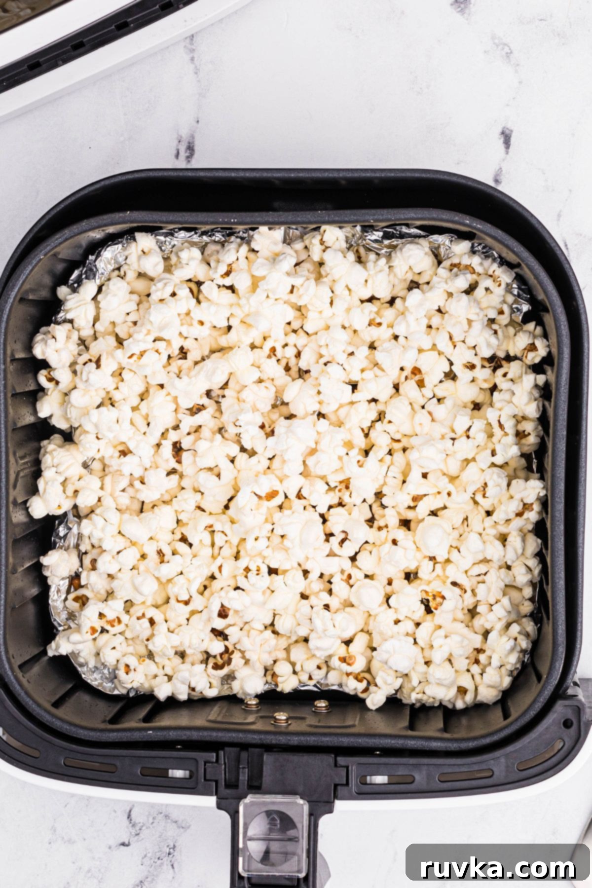 Super Bowl Air Fryer Snacks 17 Fluffy white popcorn, freshly made and piled high in the air fryer basket, ready for movie night or game day snacking.