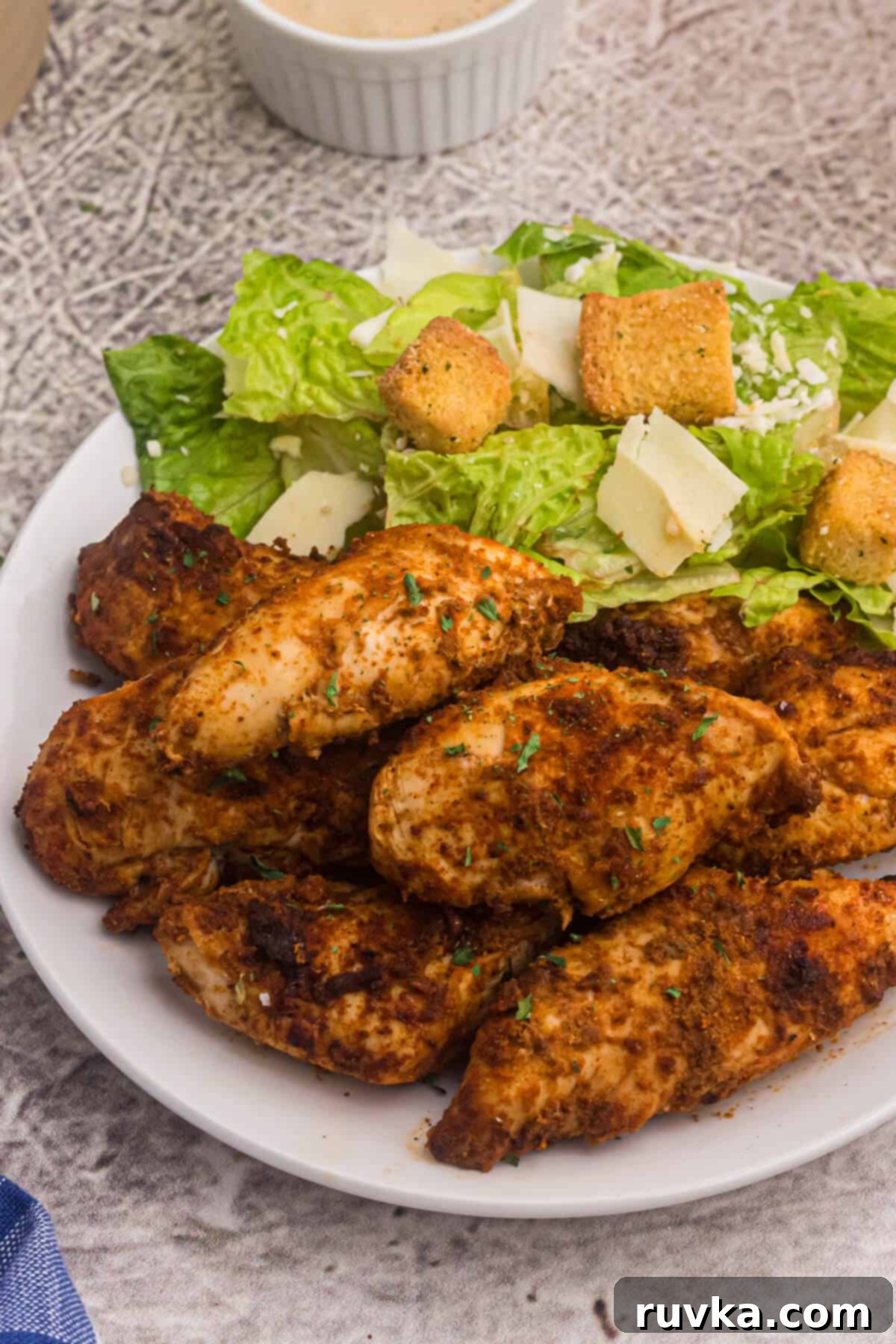 Super Bowl Air Fryer Snacks 20 Spicy blackened chicken tenders served alongside a fresh green salad on a white plate, offering a healthy and flavorful meal.