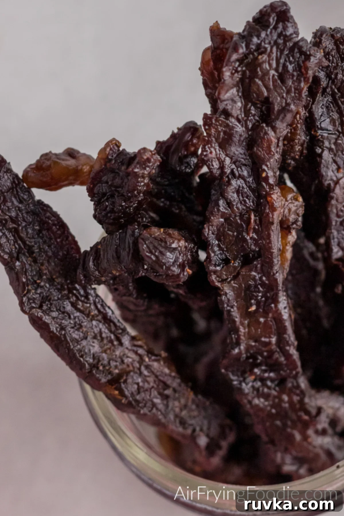 Super Bowl Air Fryer Snacks 22 Homemade beef jerky, perfectly dried and flavorful, stored in a clear glass jar, ready for snacking.