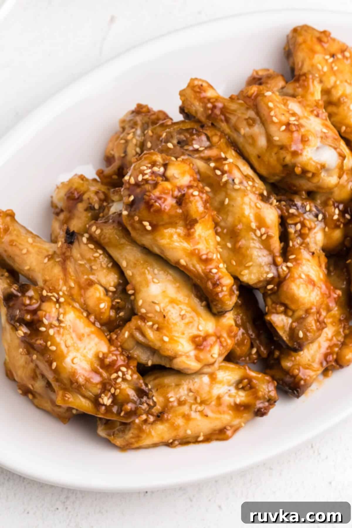 Super Bowl Air Fryer Snacks 4 Delicious honey garlic chicken wings, perfectly glazed and arranged on a clean white plate, ready to be served.