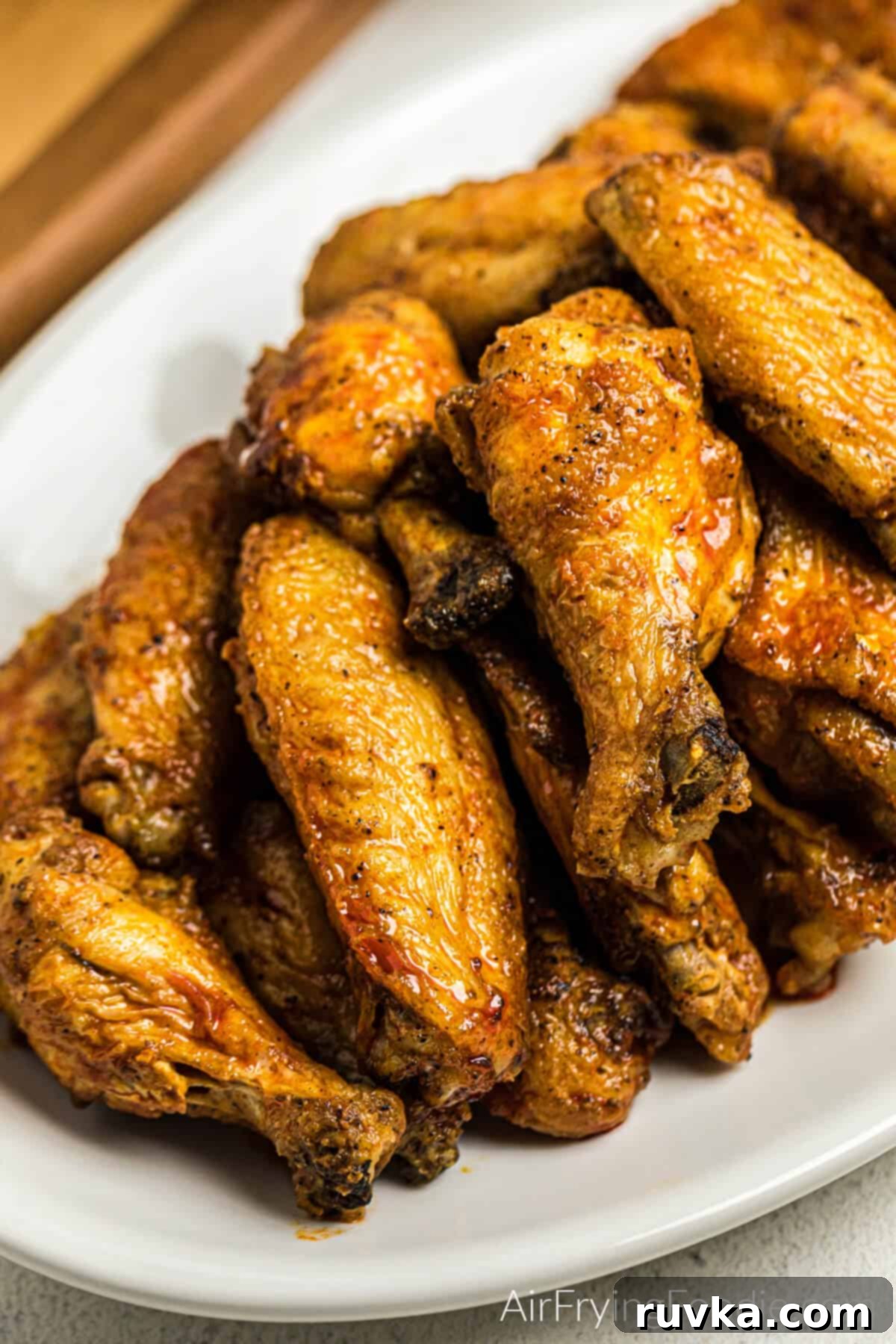 Super Bowl Air Fryer Snacks 5 Classic spicy buffalo chicken wings, glistening with sauce, served on a crisp white platter, ready for dipping.