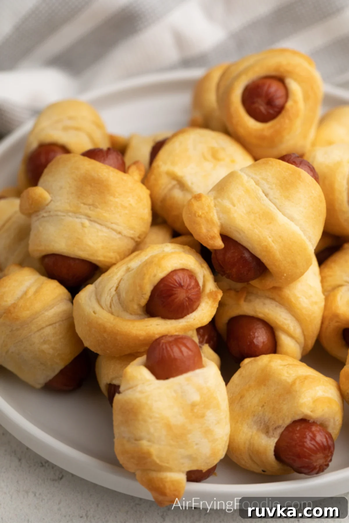 Super Bowl Air Fryer Snacks 9 Perfectly golden and crispy pigs in a blanket, neatly arranged on a white plate, ready to be dipped.