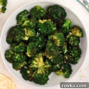 Crispy Air Fryer Veggies 9 Green cooked broccoli in a white bowl seasoned and sprinkled with parmesan cheese.