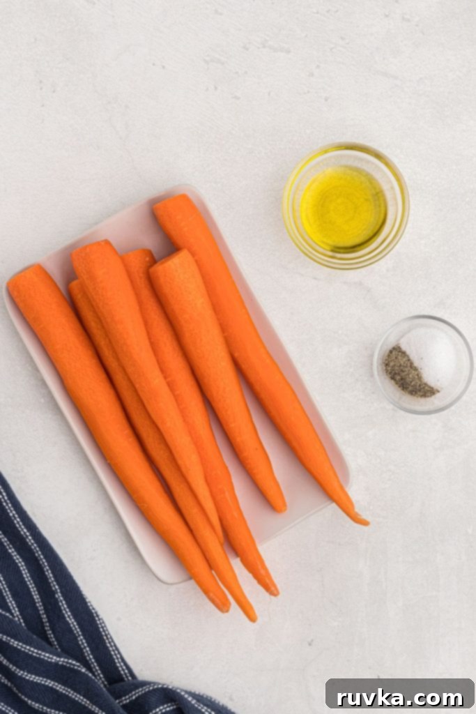 Golden Air Fryer Carrots 3 Carrots, seasonings, and olive oil on a white board with blue linen