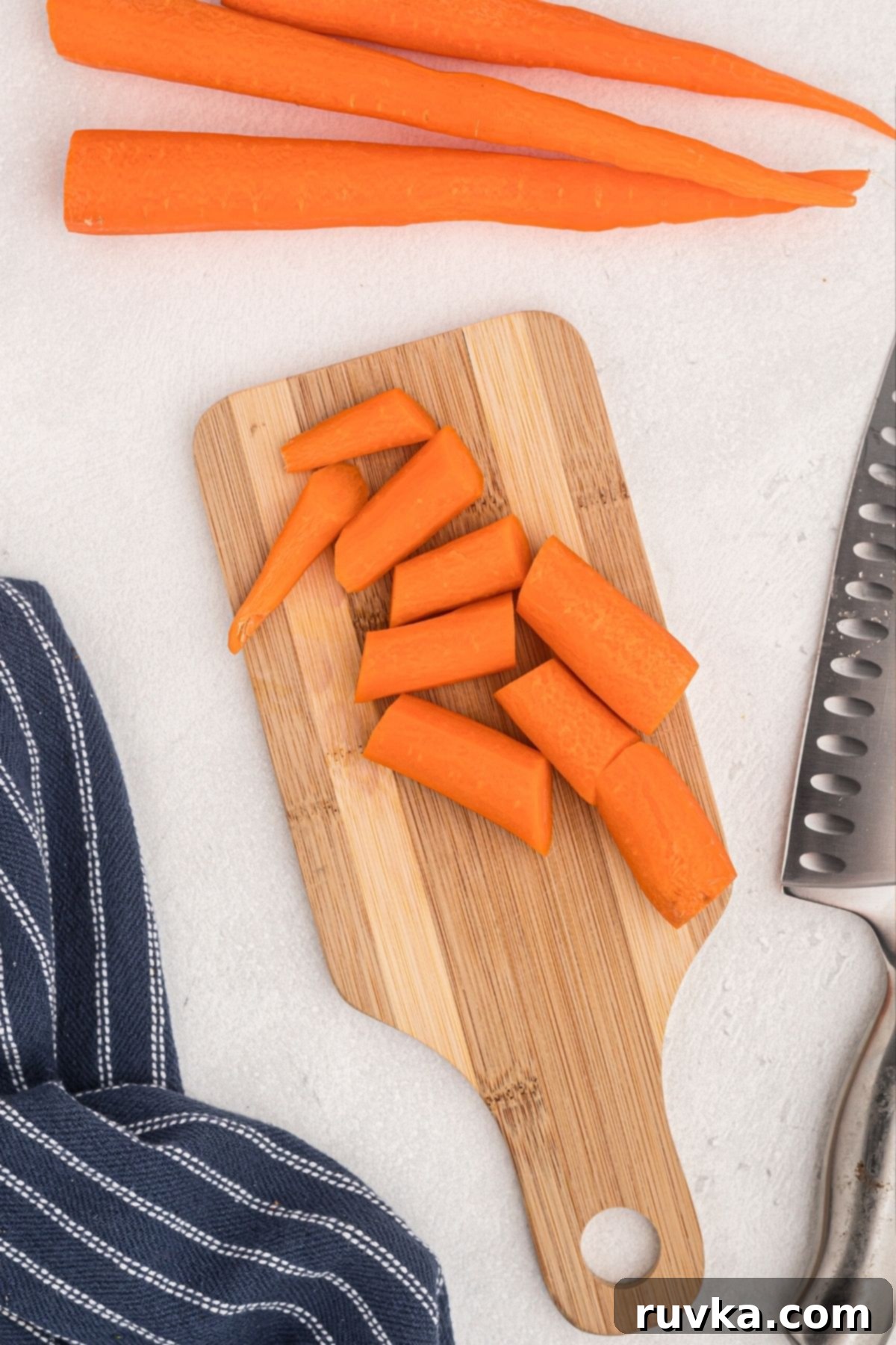 Golden Air Fryer Carrots 4 Carrots being sliced on a wooden cutting board with a knife.