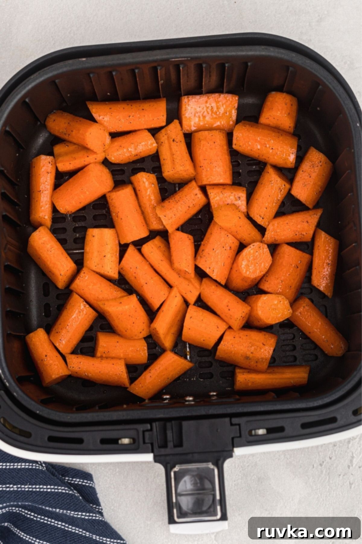 Golden Air Fryer Carrots 6 Uncooked chopped carrots in the air fryer basket after being seasoned