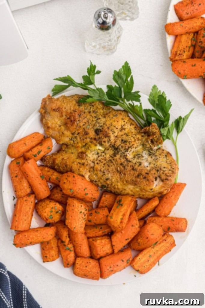 Golden Air Fryer Carrots 8 Juicy orange carrots on a plate with baked chicken on a white table.