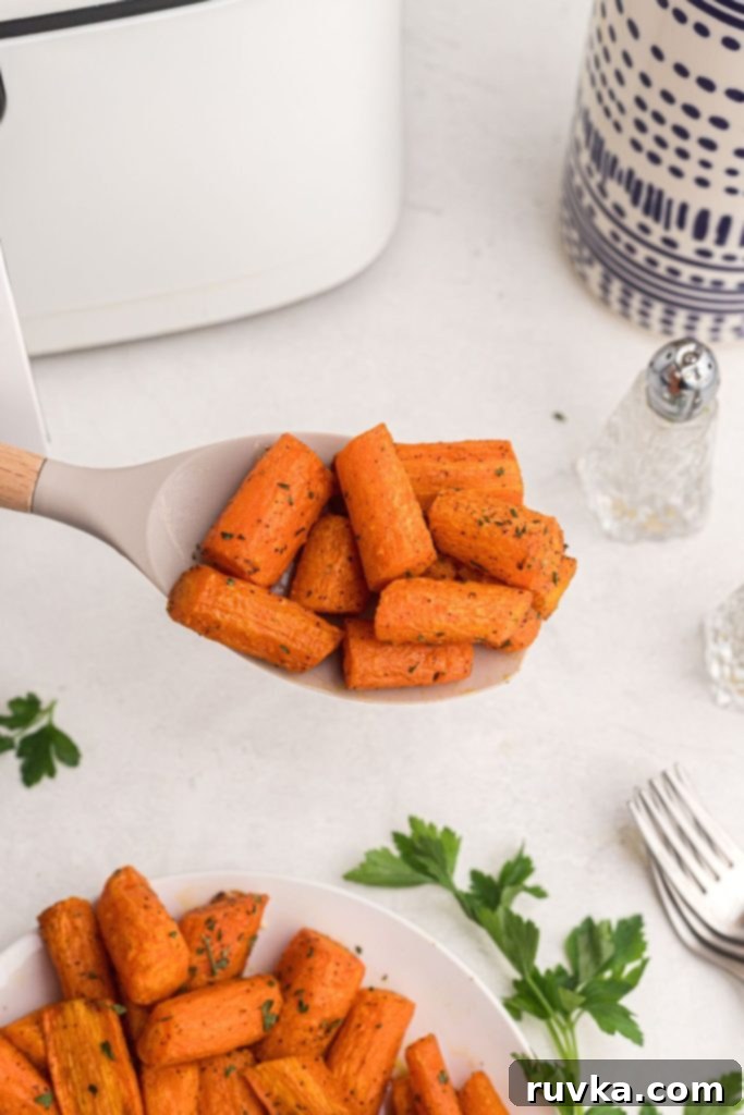 Golden Air Fryer Carrots 9 Spoonful of carrots over a white marble table with parsley and forks behind the spoon