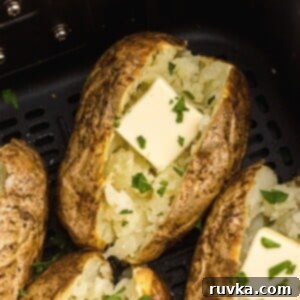 The Ultimate Air Fryer Baked Potato 9 Golden baked potatoes in the air fryer basket after being cooked with butter and parsley flakes