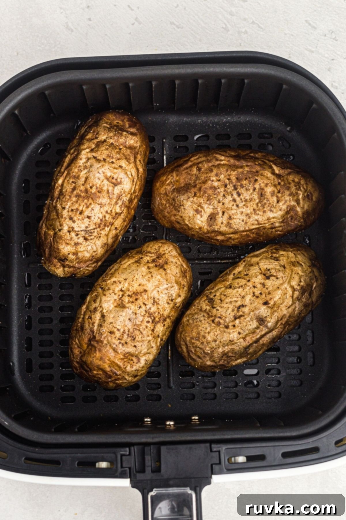 The Ultimate Air Fryer Baked Potato 6 Four potatoes in the air fryer basket after being cooked.