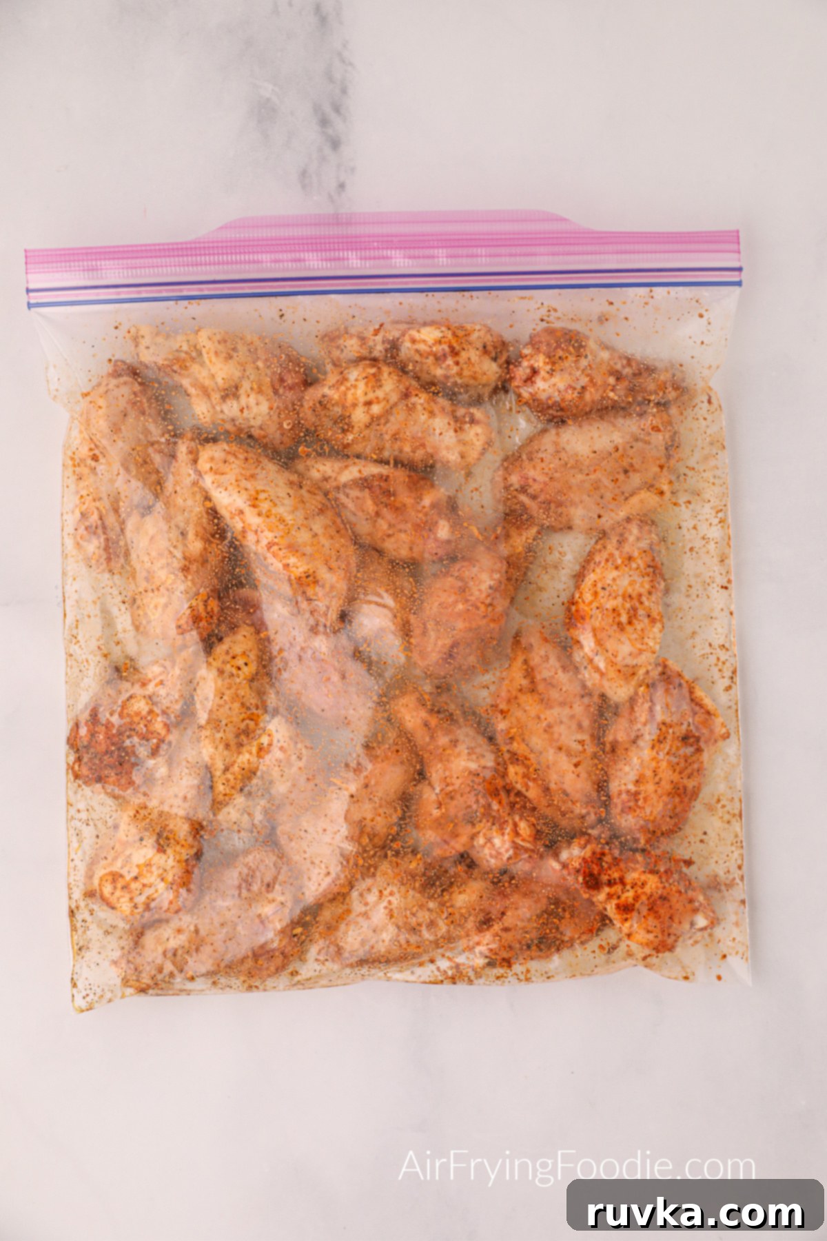 Zesty Air-Fried Lemon Pepper Wings 4 A large Ziploc bag containing chicken wings, olive oil, cornstarch, and various seasonings, all mixed and combined evenly.