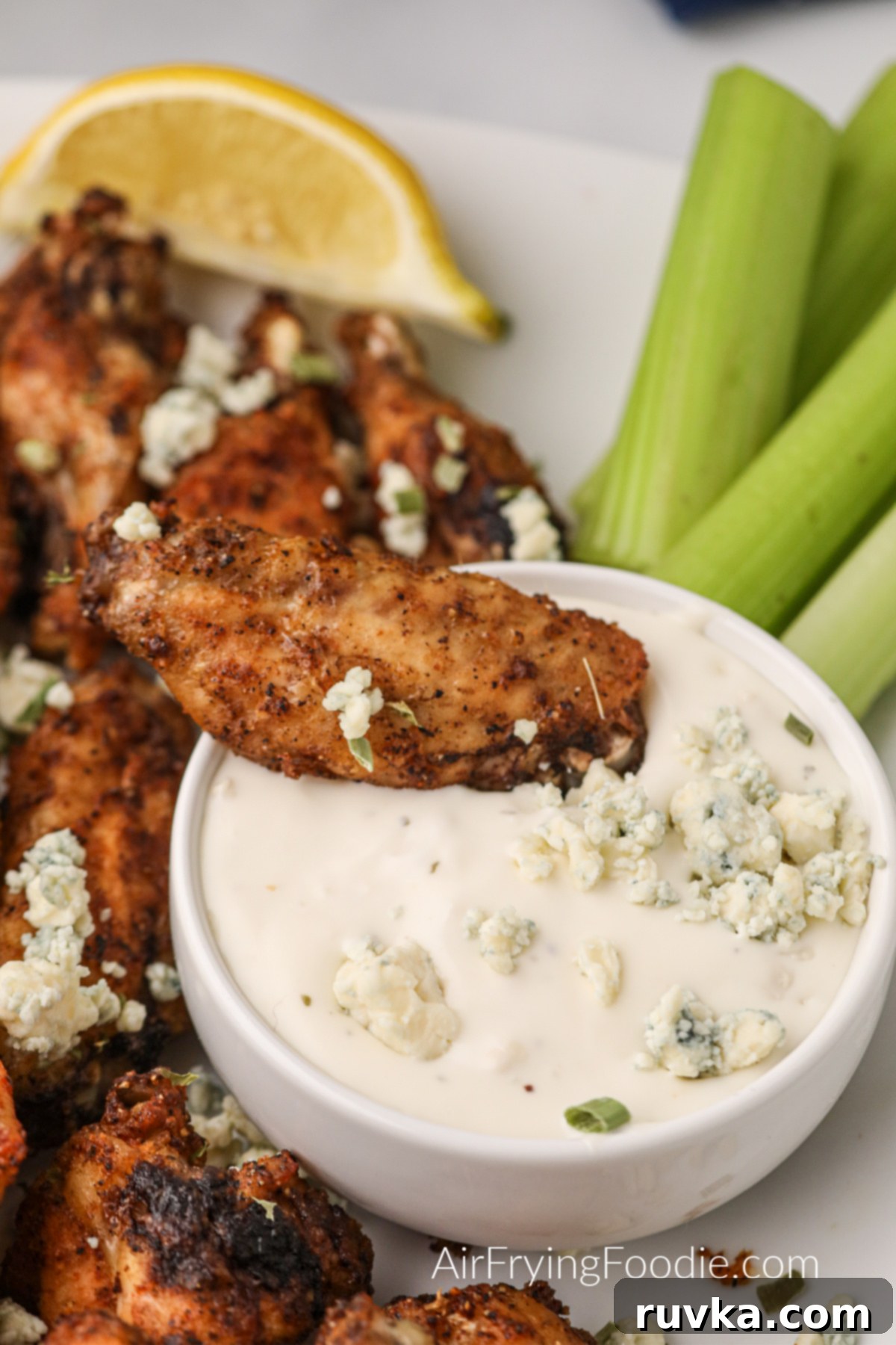 Zesty Air-Fried Lemon Pepper Wings 7 A perfectly cooked lemon pepper wing being dipped into a creamy blue cheese dressing, with crisp celery sticks on the side for a classic pairing.