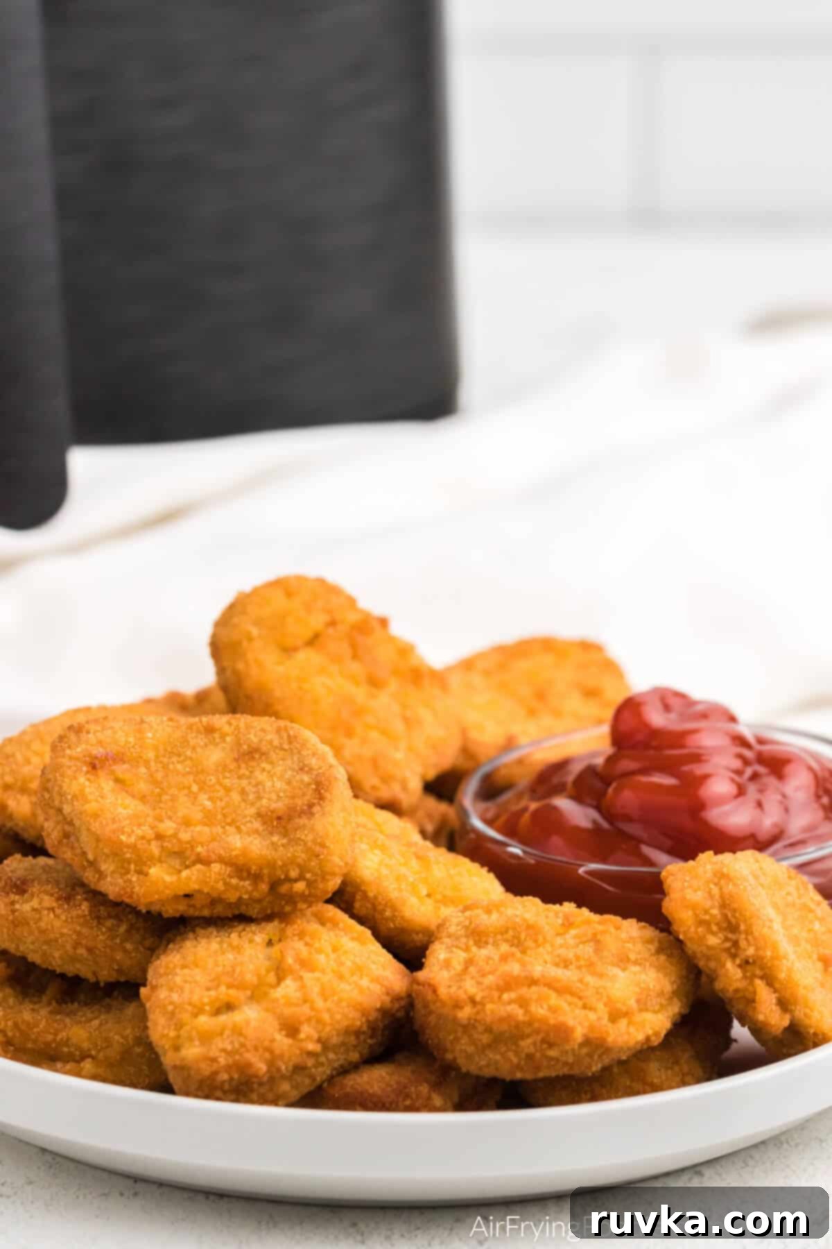 Golden Air Fryer Nugget Perfection 2 Crispy air fried chicken nuggets on a white plate with a small portion of ketchup for dipping, highlighting their golden-brown perfection.