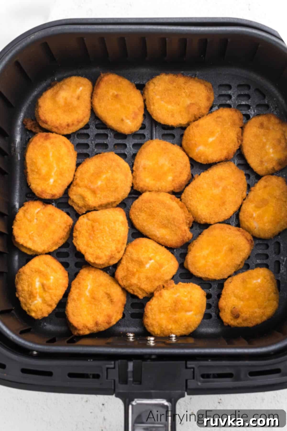 Golden Air Fryer Nugget Perfection 4 Frozen chicken nuggets carefully arranged in a single layer within an air fryer basket, ready for cooking.