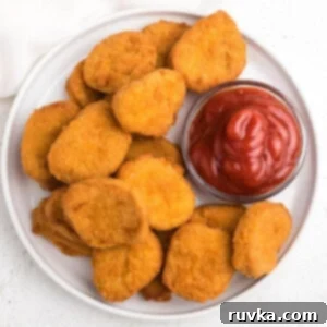 Golden Air Fryer Nugget Perfection 6 overhead photo of air fryer chicken nuggets served on a white plate with ketchup.