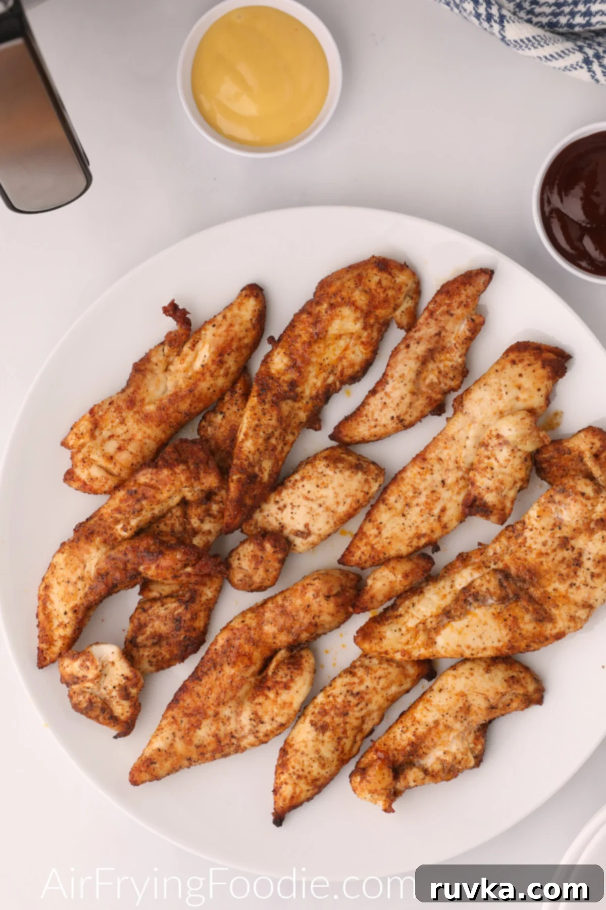 Naturally Crispy Air Fryer Chicken Tenders 2 Grilled Chicken Tenders cooked and seasoned and served on a white plate.