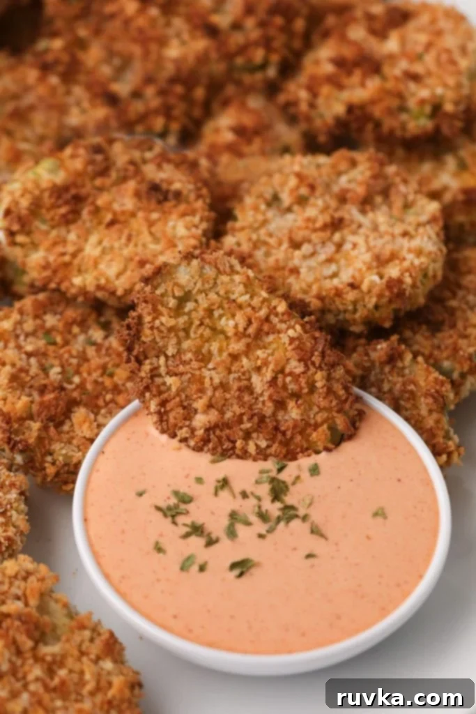 Crispy Air Fryer Fried Pickles 2 Golden battered fried pickle being dipped into a creamy sauce, highlighting its crispy coating.