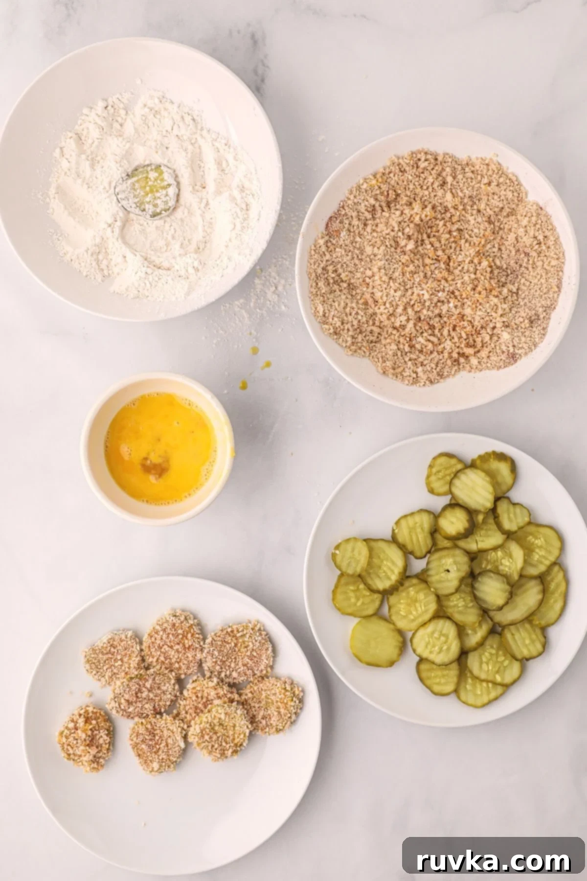 Crispy Air Fryer Fried Pickles 5 Three bowls showing the prepared dredging station: seasoned flour, whisked eggs, and panko breadcrumbs.