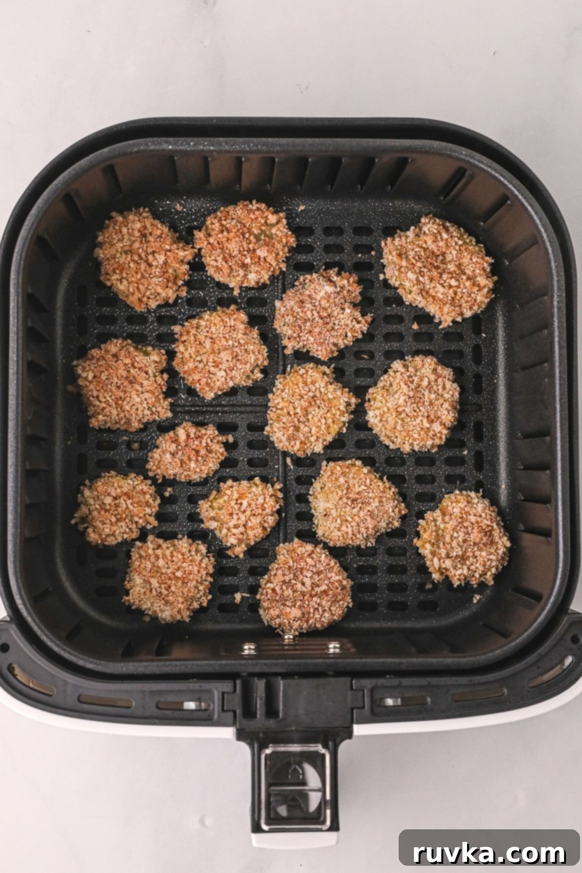 Crispy Air Fryer Fried Pickles 6 Perfectly battered pickle slices arranged in a single layer in the air fryer basket, ready for cooking.