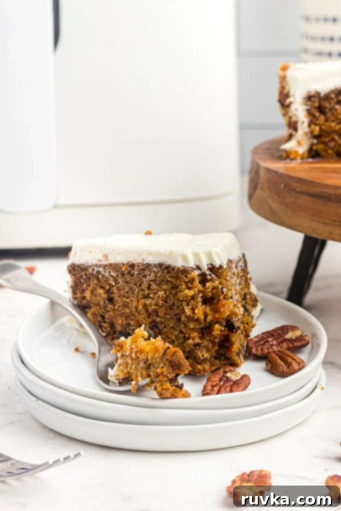Air Fryer Carrot Cake Delight 2 Slice of carrot cake with a bite on a fork and scattered pecans on the table