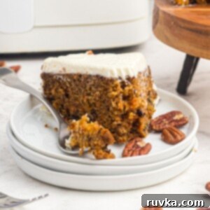 Air Fryer Carrot Cake Delight 12 Slice of carrot cake on a white plate with a fork holding a bite of the cake