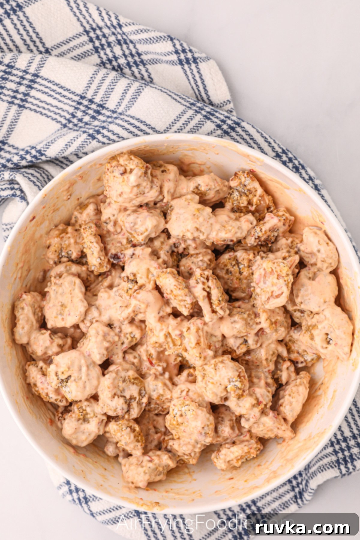 Crispy Air Fryer Bang Bang Shrimp 6 Shrimp in a shallow bowl covered in bang bang sauce.