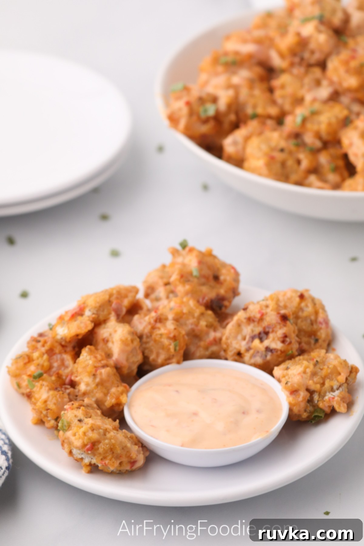 Crispy Air Fryer Bang Bang Shrimp 8 Bang bang shrimp served on plates and with a side of dipping sauce.