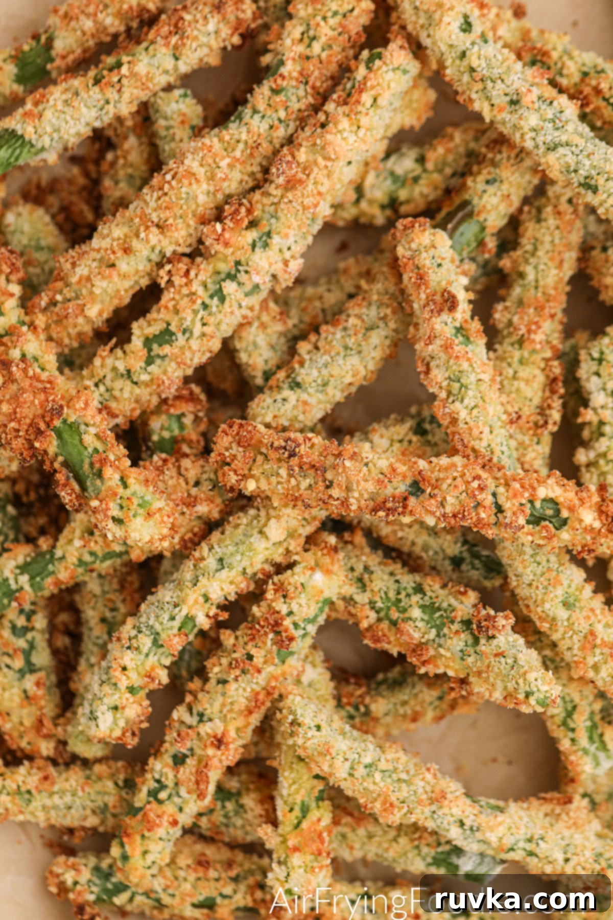 Air Fryer Crispy Green Bean Sticks 8 A close-up view of perfectly golden and crispy air fryer green bean fries, showing the textured breading and tender green bean inside.
