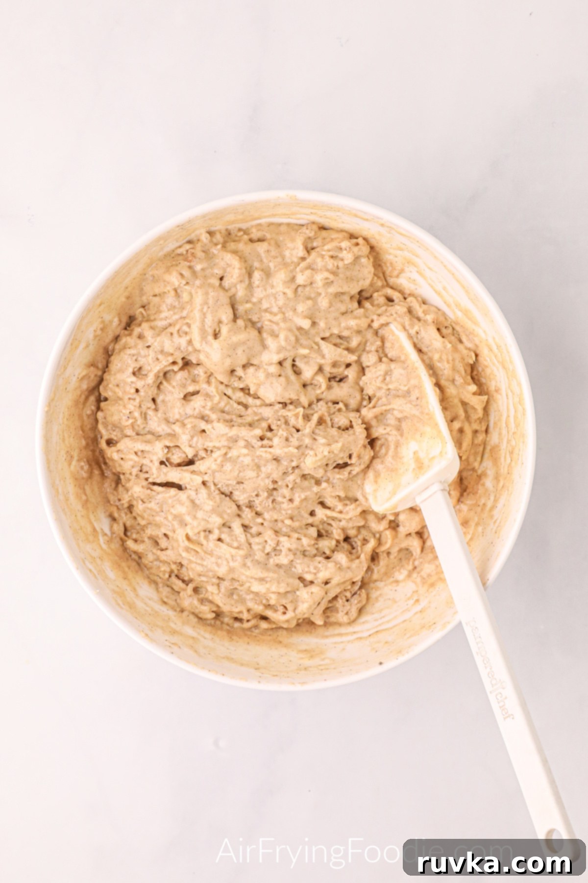 Easy Air Fryer Apple Fritters 5 The prepared apple fritter dough, a thick batter filled with shredded apples, sits in a bowl, ready to be scooped into the air fryer.