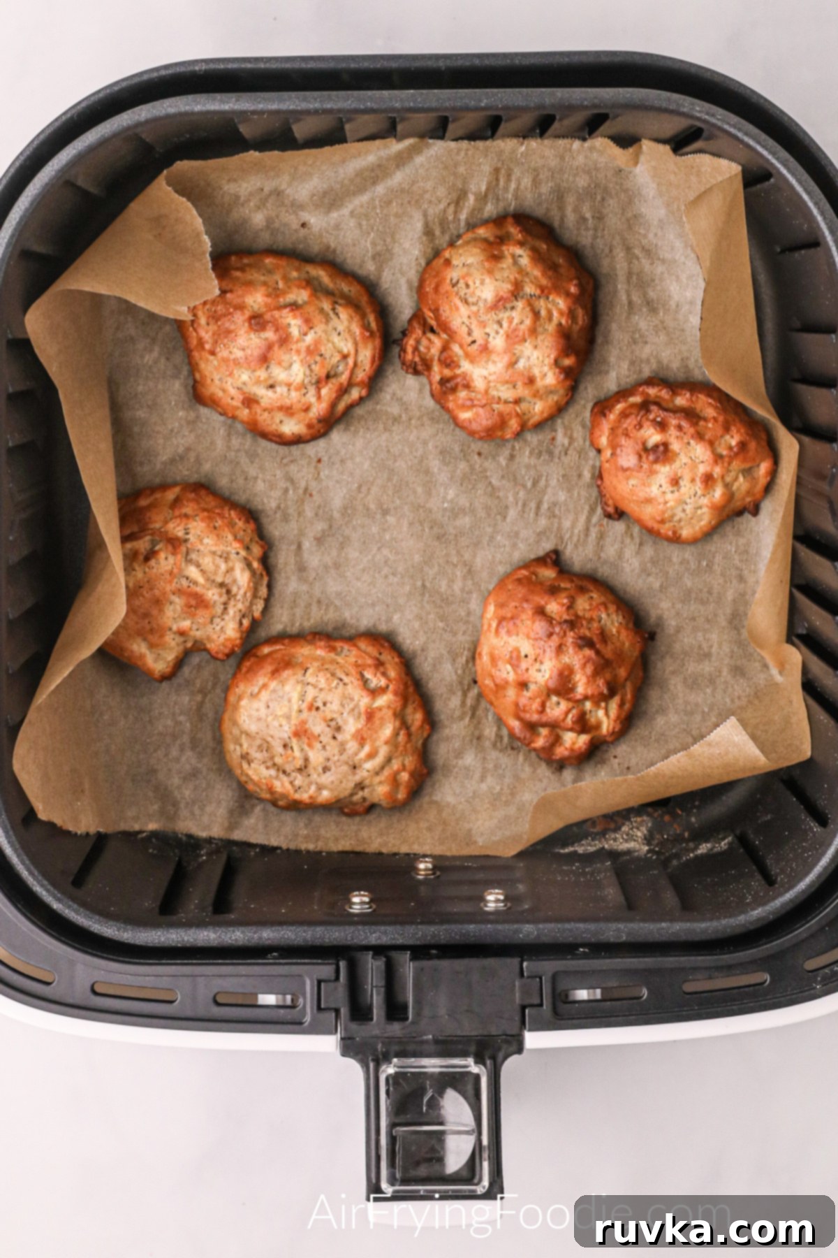 Easy Air Fryer Apple Fritters 7 Perfectly cooked, golden brown apple fritters nestled in the air fryer basket, ready for glazing.