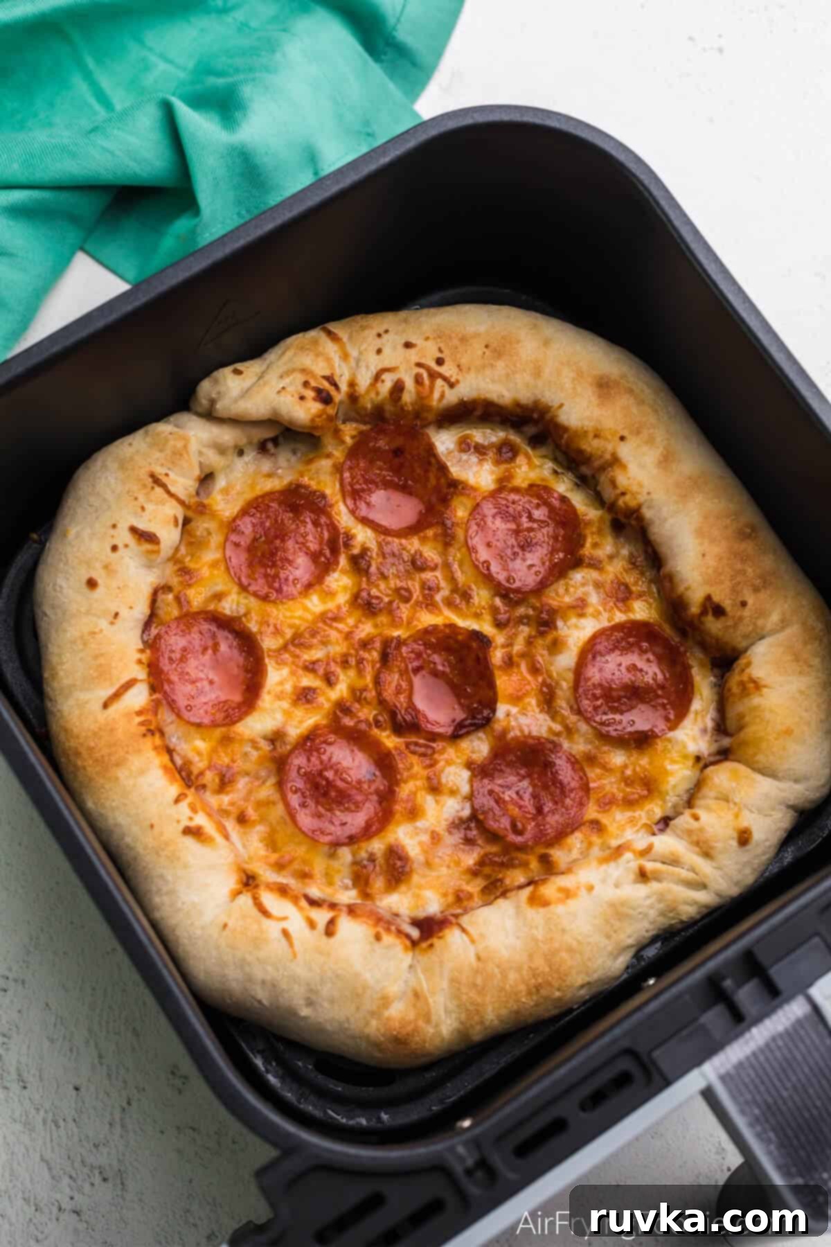 Crispy Air Fryer Pizza 2 Freshly cooked Air Fryer pizza with melted cheese and pepperoni, resting in the basket of an air fryer.
